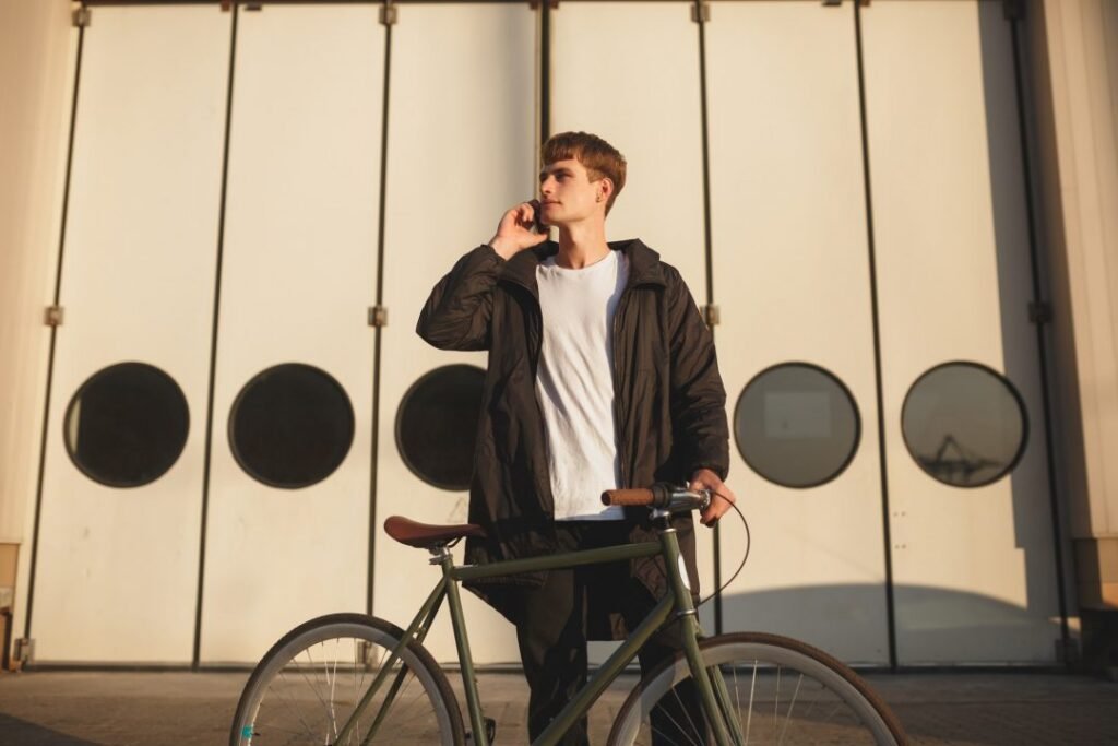 portrait of boy in white t shirt and down jacket standing with bicycle on street.jpg